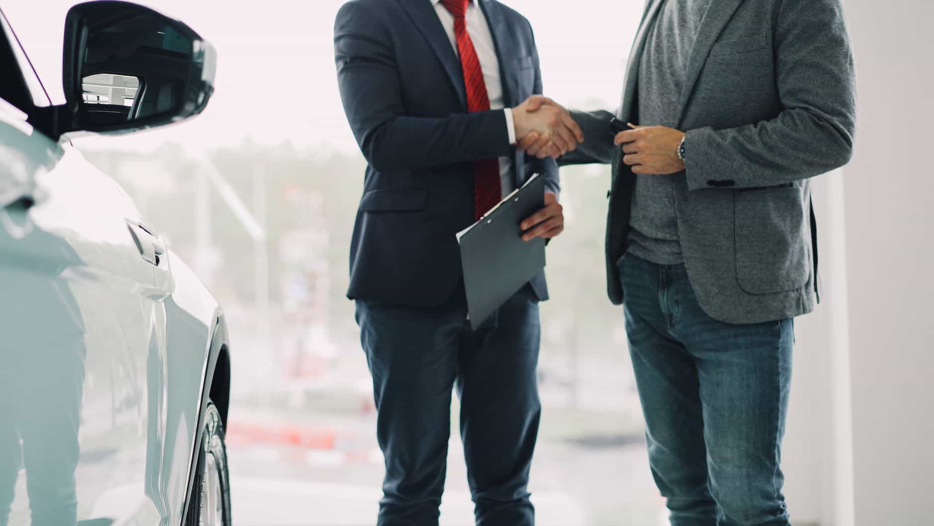 business deal handshake in car showroom